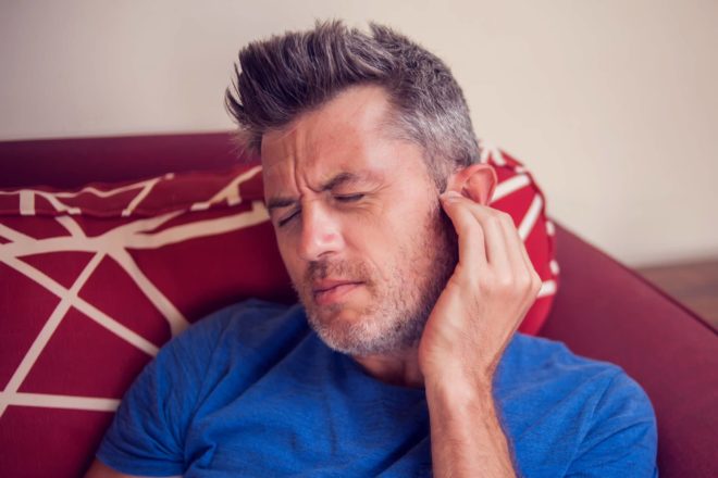 A man holding his painful ear due to his tinnitus symptoms in St. Joseph Michigan. 