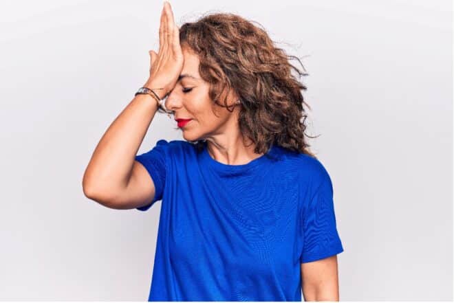 woman in blue t shirt with hand to head